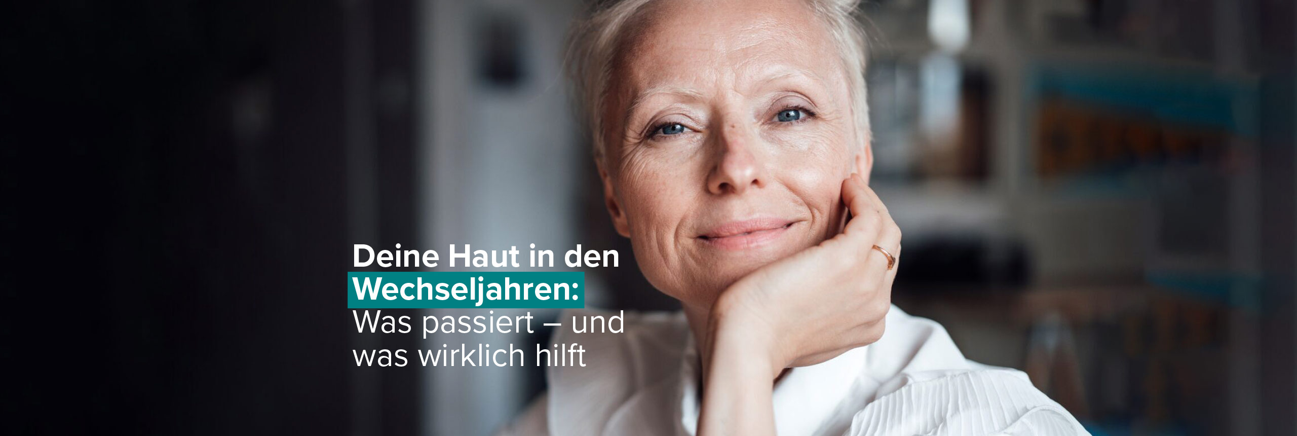 Strahlende Frau ab 50 mit natürlichem Look vor dunklerem Hintergrund, Hand stützt Gesicht ab | Deine Haut in den Wechseljahren: Was passiert – und was wirklich hilft | Merz Aesthetics