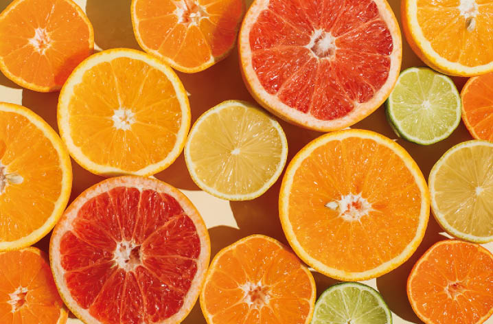 Aufgeschnittene Zitrusfrüchte wie Orangen, Grapefruits und Limetten liegen dicht nebeneinander, Nahaufnahme von oben