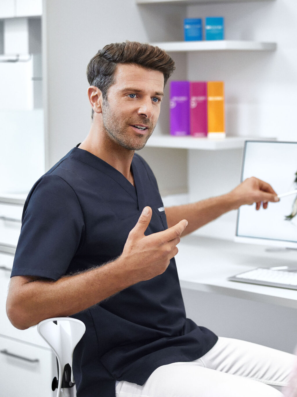 Arzt von Merz Aesthetics® zeigt einer Patientin an einem Bildschirm Behandlungsmöglichkeiten.